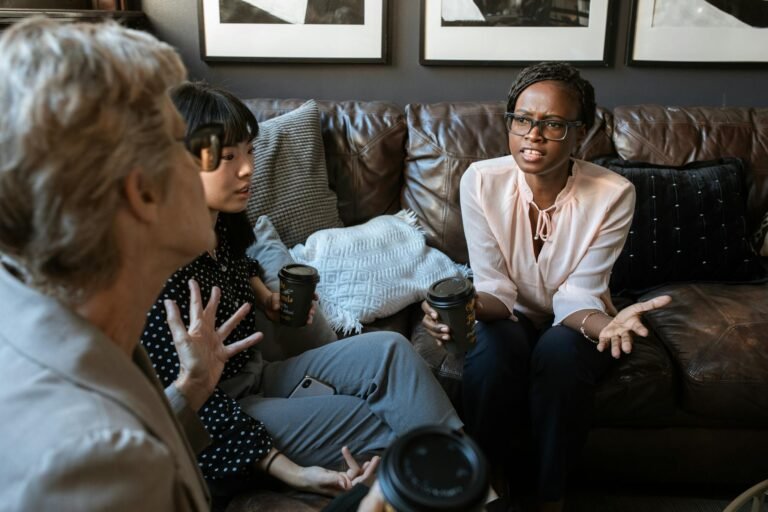 Three diverse entrepreneurs discussing ideas over coffee in a modern workspace.